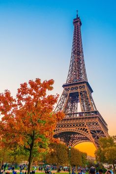 the eiffel tower is surrounded by trees and people walking in front of it