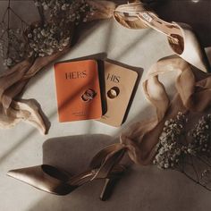 a pair of high heeled shoes sitting on top of a table next to an orange book