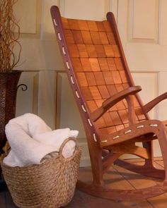 a wooden rocking chair next to a wicker basket with a white towel on it