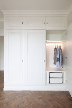 a white closet with clothes hanging on the doors and drawers in it's center