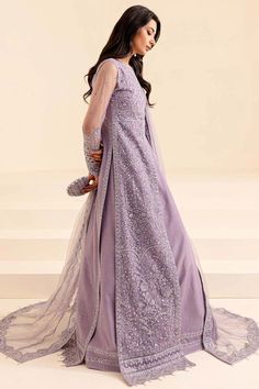 a woman in a long purple dress with sheer sleeves and an intricate lace detail on the back