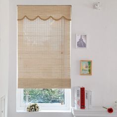 a room with a window covered in blinds and pictures on the wall next to it