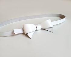 This beautiful and original belt is made of white firm natural leather. The leather bow on the front will perfectly accentuate your waist and highlight your personal style. The belt will look great on dresses and skirts. Belt closes with metal snap, which is hidden under leather bow- put belt tail through the loop and close it. The belt has three holes to adjust  your waist.  The size chart shows the waist circumference from the first hole to the third hole. Main colour: white  Material: White n Modern White Belt For Formal Occasions, Modern White Formal Belt, Formal White Bow, Chic White Bow For Party, Adjustable Detachable White Bow, Bow Sash, Bow Belt, Silky Dress, Leather Bow