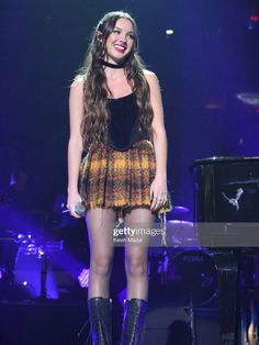 a woman standing on top of a stage next to a piano