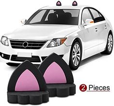 two pieces of black and pink cat ears are in front of a white car