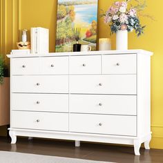 a white dresser with flowers and pictures on it