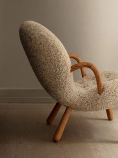 a chair made out of sheep's wool with wooden arms and legs, sitting on a hard wood floor