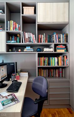 a desk with a computer monitor, keyboard and mouse on it in front of a bookshelf