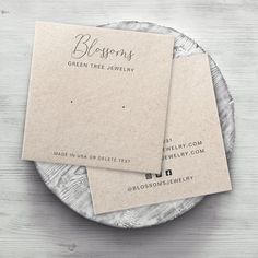 two business cards sitting on top of a white and gray plate next to each other