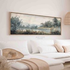 a white couch sitting under a painting in a living room