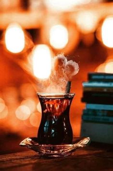 a cup with steam rising out of it sitting on top of a table next to books