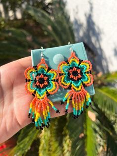 Huichol beaded flower earrings are carefully made by talented hardworking artisans in Mexico. A beautiful accessory to match any outfit and embrace the artistry behind this creation Each set comes with a protective jewelry case Measurements: -Flower + strings: 4" -Length: 4 1/2" Handmade Artisan Multicolor Flower Earrings, Artisan Handmade Multicolor Flower Earrings, Artisan Multicolor Handmade Flower Earrings, Handmade Multicolor Beaded Earrings In Flower Shape, Artisan Multicolor Flower Drop Earrings, Unique Multicolor Beaded Flower Earrings, Multicolor Artisan Flower Drop Earrings, Traditional Colorful Beaded Flower Earrings For Festivals, Traditional Flower Earrings With Colorful Beads For Festival