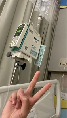 a hand making the peace sign in front of an iv machine