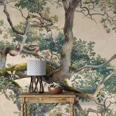 a table with a lamp on it in front of a tree wallpapered background