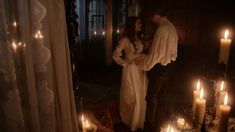 a man and woman standing next to each other in a room with candles on the floor