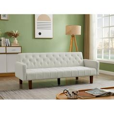 a living room with a white couch and table in front of a green painted wall