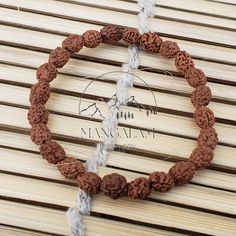 a bracelet made out of brown and white rope on top of a wooden table next to a sign