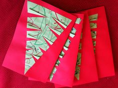 four pieces of red paper with green and white designs on them sitting on a red surface