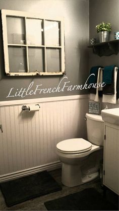 a white toilet sitting in a bathroom next to a sink under a window with shutters