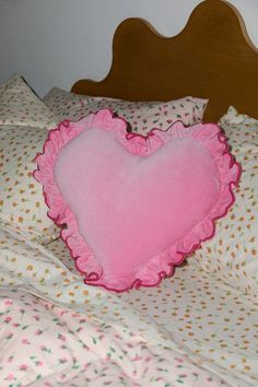 a pink heart shaped pillow sitting on top of a bed