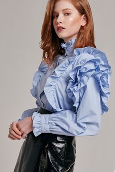 Details This button-up top channels vintage elegance with its high neckline and ruffle details. - High neckline - Ruffles on shoulders and around neck - Button closure in front - Comes in two colors: Skyblue / White Content + Care - 100% Cotton - Dry clean Size + Fit Model is 5'8" and wearing size S Luxury Traditional Blouse With Ruffles, Luxury Multicolor Ruffled Tops, Luxury Dress With Ruffles And Ruffled Collar, Luxury Ruffled Elegant Shirt, Luxury High Neck Blouse For Fall, Luxury Glamorous Blouse With Ruffles, Luxury Designer Ruffled Sets, Luxury Designer Blouse Piece With Ruffles, Luxury Feminine Dress With Ruffled Collar