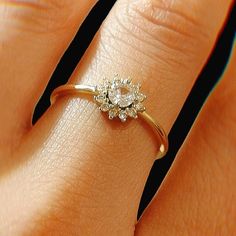 a woman's hand with a diamond ring on top of her finger and the other hand holding it