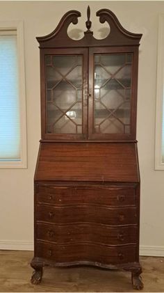 an old wooden desk with glass doors and drawers