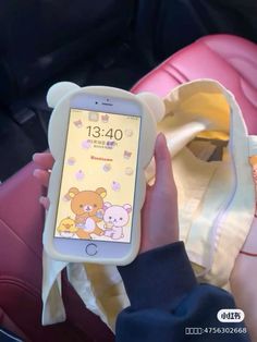 a person holding up a cell phone with a bear design on the front and back