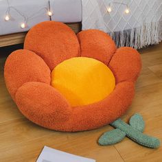 an orange flower shaped chair sitting on top of a wooden floor