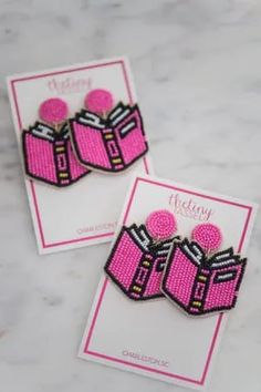 two pink and black earrings on top of a card