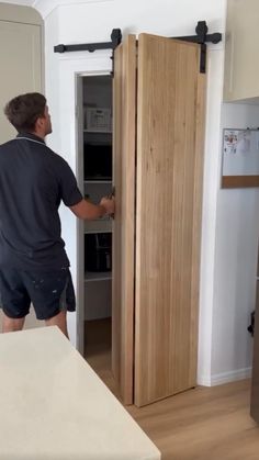 a man is opening the door to his new kitchenette in an empty room with white walls and wood flooring