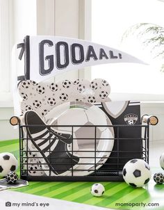 a table with soccer balls and plates in a basket next to a sign that says 1 goal