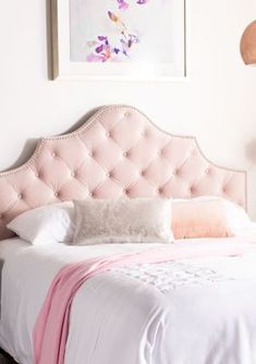 a pink bed with white sheets and pillows on top of it next to a painting