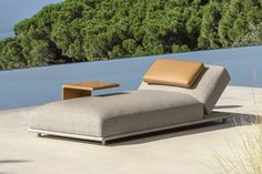 an outdoor chaise lounge with a view of the ocean in the backround