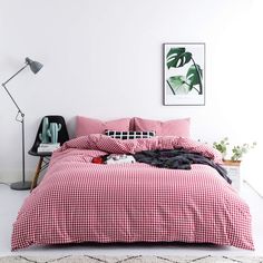 a bed with red and white checkered sheets in a room next to a lamp