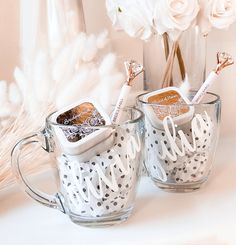 two coffee mugs with personalized items in them