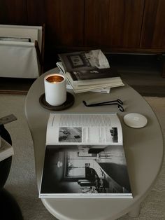 a coffee table with magazines and a candle on it