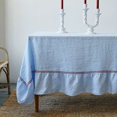 two white candles are sitting on top of a blue tablecloth with red and white trim