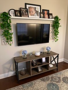 a flat screen tv mounted to the side of a wall next to a shelf with pictures on it