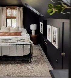 an attic bedroom with black walls, white bedding and pictures on the wall above it