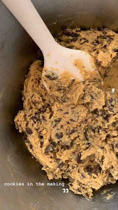 a mixing bowl filled with batter and chocolate chip cookies in the making process, ready to be mixed together