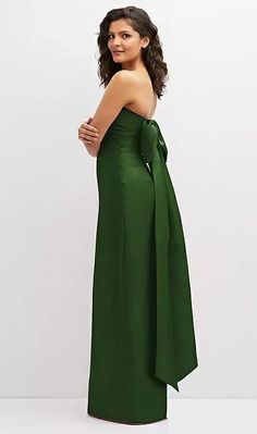 a woman wearing a green dress with a large bow at the waist and one shoulder