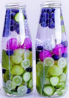 two glass vases filled with different types of fruit and veggies on a table