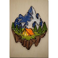 a wooden wall hanging with a tent in the middle and mountains on it's side