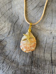 a rock with a starfish on it is sitting on a roped cord necklace