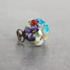 This romantic Glass ladybug flower ring is a perfect gift for women. It's very tender and unique! Set Matching bracelet: https://www.etsy.com/listing/161559547 Matching earrings: https://www.etsy.com/listing/200833152 Matching pendant: https://www.etsy.com/listing/161556072 Dimensions: the ring is adjustable. The bead is 2.2-2.4cm in diameter. Materials: artist lampwork bead, metal fittings. Colors used: blue, white, lilac, violet, green. Please, note, each bead is made by hand and may differ sl Adjustable 3d Flowers Jewelry, Whimsical Adjustable Ring Jewelry, Whimsical Adjustable Ring, Whimsical Adjustable Jewelry Ring, Whimsical Adjustable Jewelry For Gifts, Adjustable Whimsical Jewelry For Gifts, Adjustable Whimsical Ring, Whimsical Adjustable Jewelry As Gift, Delicate Flower Shaped Ring For Gift