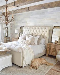 a dog laying on the floor in front of a bed with white sheets and pillows