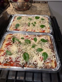 two pans filled with pizza sitting on top of an oven