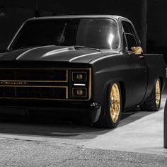 a black truck with gold rims parked in a garage