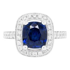 This lovely 18 carat white gold cluster ring is beautifully centred with a 2.52ct blue cushion cut sapphire, mounted in a four claw, open back setting. The vibrant stone is further highlighted by a halo of 22 round brilliant cut diamonds, all micro claw set around the beautiful sapphire. Finally, 30 round brilliant cut diamonds decorate the delicate shank and an open work gallery, making the total diamond weight 0.69ct. Stamped 750. UK finger size 'L’. Gia Certified Cushion Cut Sapphire Ring, Sapphire Cushion Cut Ring With Center Stone, Cushion Cut Lab-created Sapphire Ring In Fine Jewelry Style, Classic Blue Radiant Cut Sapphire Ring, Cushion Cut Lab-created Sapphire Ring With Halo Setting, Formal Cushion Cut Lab-created Sapphire Ring, Cushion Cut Lab-created Sapphire Ring, Blue Cushion Cut Halo Ring With Center Stone, Lab-created Sapphire Diamond Ring In Cushion Cut